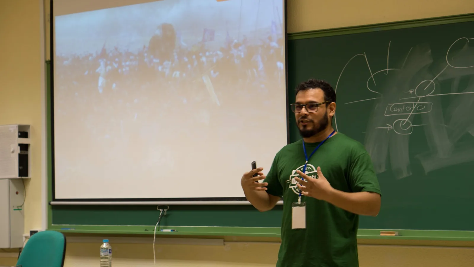Nico dando una charla en un aula, con la pizarra llena de diagramas